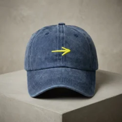 Boné da Seta Amarela em cor Denim, feito de algodão escovado, em cima de um pilar de cimento.