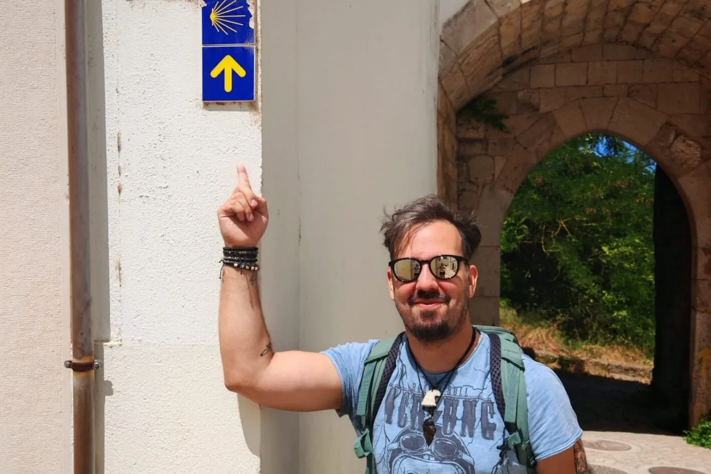Peregrino a apontar para sinal do Caminho numa parede