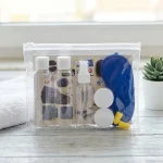 Plano aproximado do Necessaire Ultreya composto por duas embalagens de líquidos, duas caixinhas pequenas, uma venda para os olhos, os tampões para os ouvidos, e o postal checklist